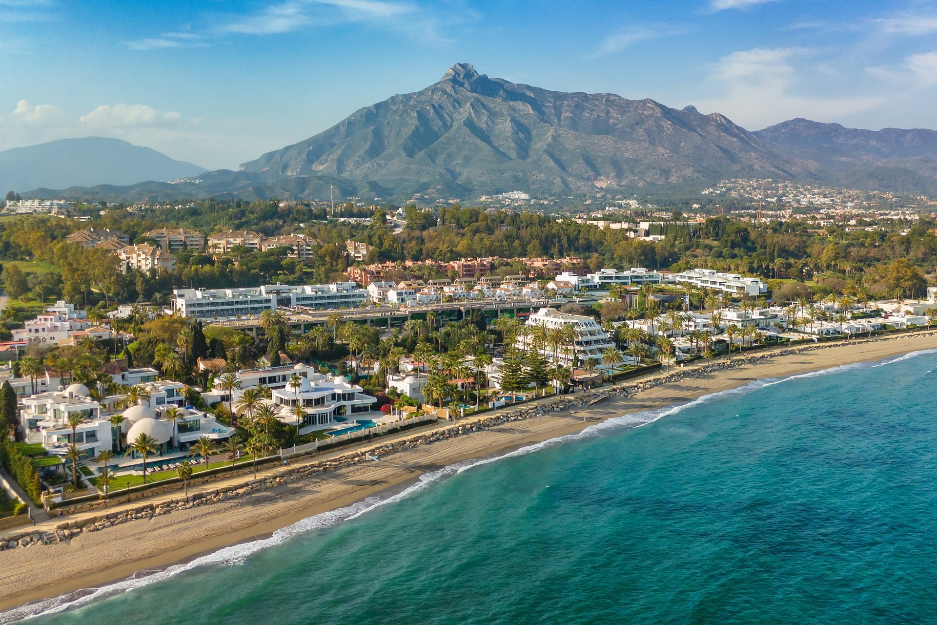 Luxury beachfront villa with ocean view, private pool, and mountain backdrop.